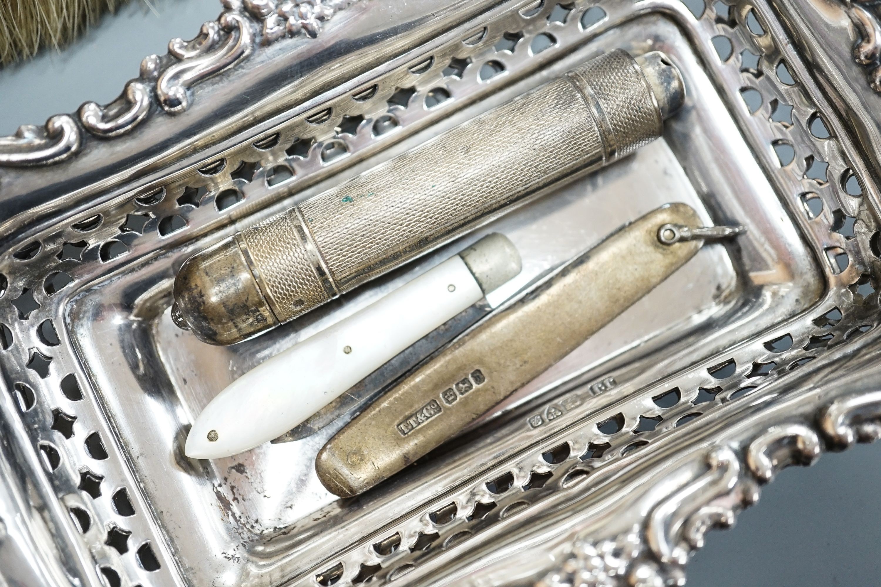 A pair of Edwardian pierced silver bonbon dishes, Chester, 1902, 16.1cm, 4.5oz, a silver and mother of pearl fruit knife, silver cased penknife and silver mounted clothes brush and a modern silver cased pocket torch.
